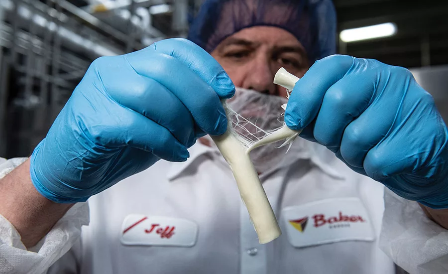Master cheesemaker Jeff LeBeau showcases a stick of string cheese. Baker Cheese uses traditional low-moisture/part-skim mozzarella cheesemaking procedures to get the best stretch and stringability.
