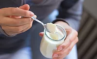 woman grabbing a spoonful of yogurt woman grabbing a spoonful of yogurt