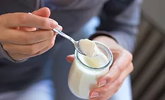 woman grabbing a spoonful of yogurt