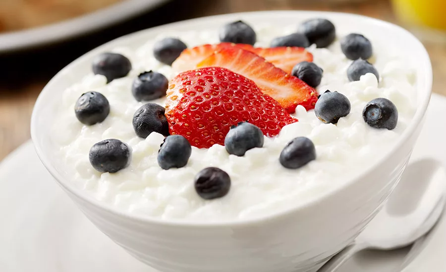 bowl of cottage cheese with strawberries and blueberries on top