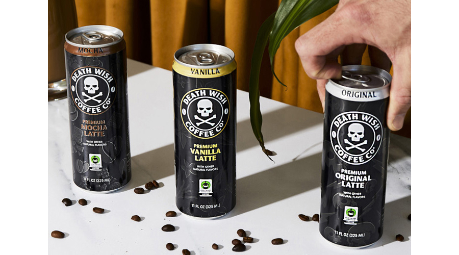 Death Wish Coffee Co. Premium canned lattes in three flavors on a white table, a hand is opening one can and coffee beans are strewn on the table.