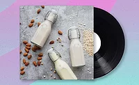 Album cover with glass bottles of dairy alternative milk, almonds and oats strewn on the table.