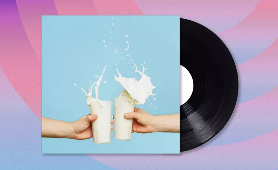 Album with two hands toasting with glasses of milk, the milk spilling over. The album is half-way out of the sleeve, patterned background.
