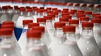 Bottles of milk with red caps on the assembly line
