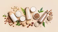 Jars of milk,small bowls of rice, glasses of milk are laid out surrounded by nuts, leaves and oats Jars of milk,small bowls of rice, glasses of milk are laid out surrounded by nuts, leaves and oats on a tan-colored table.