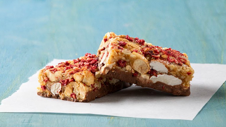 Snack bar in two pieces on a paper towel on a blue patterned table.