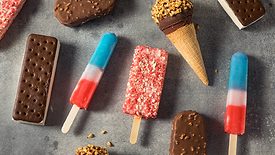Variety of ice cream including ice cream sandwiches, popsicles, and ice cream bars laid out on a table.