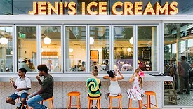 Customers sitting on orang bar stools outside of Jeni's ice cream store eating ice cream.