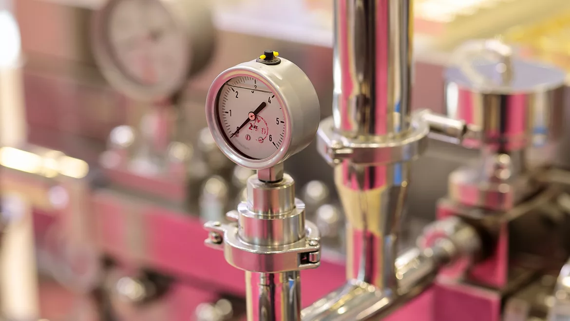 Close up look at a pump and valve, the bigger machine in the blurred background.