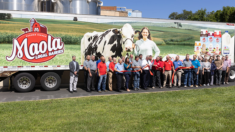 Maola Local Dairies staff posing in front of the side of a container truck.