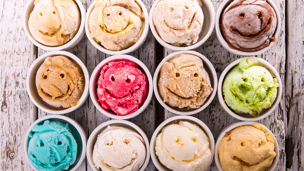 Image of rows of cups of different flavored ice cream, each one with a smiley face carved on the scoop.