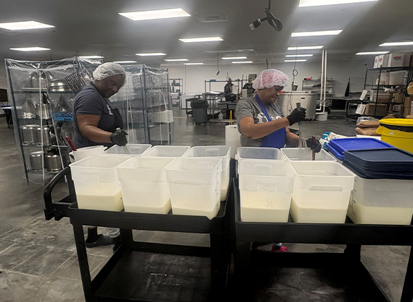 Two Frios employees mixing tubs in the processing facility.