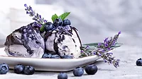 Vanila and blueberry ice cream with lavender on blue background.